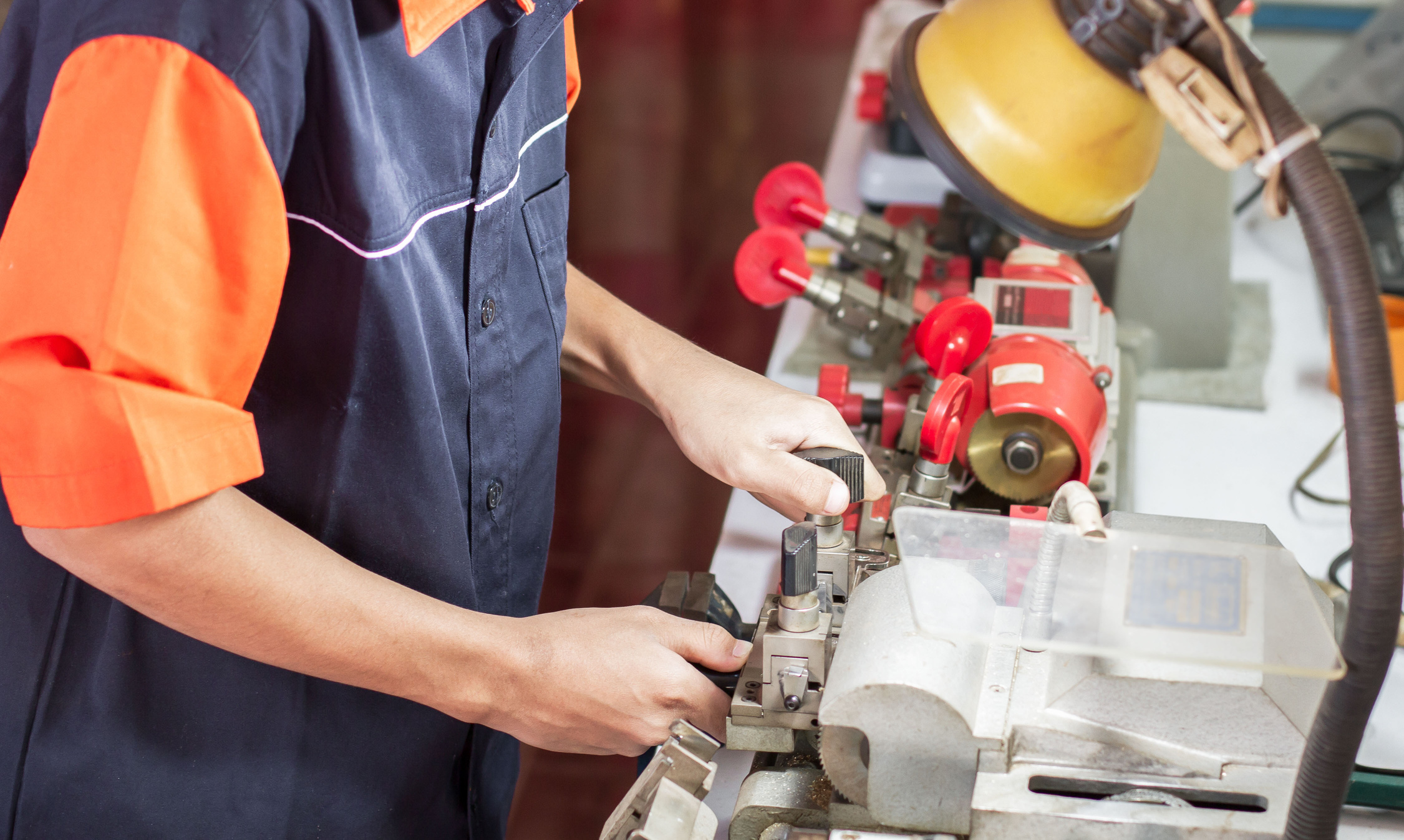 Locksmith in workshop makes new key. Professional making key in locksmith.